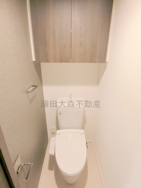 拡大写真:ハーモニーレジデンス羽田天空橋 3階305の吊戸棚と温水洗浄便座付きのトイレ